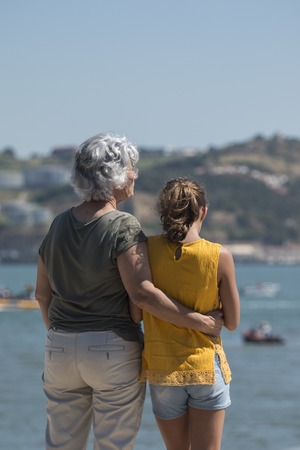 View of a young girl with her grandmother gazing the river.