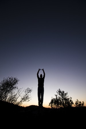 View of the silhouette of a man on top of a hill.