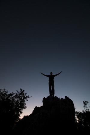 View of the silhouette of a man on top of a hill.