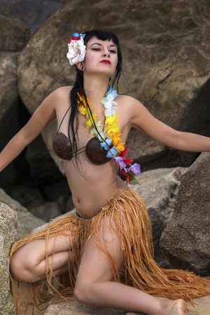 Beautiful and cute hula themed pinup girl fashion on the rocky shoreline.の写真素材