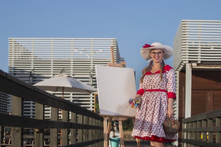 Cute pinup girl in the beach painting the landscape.の写真素材