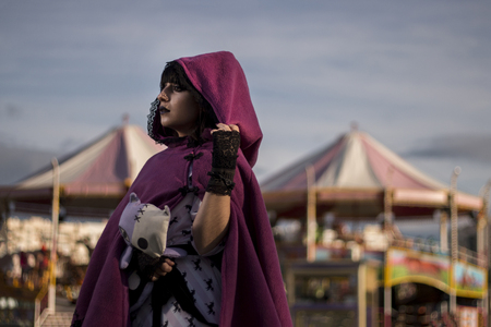 Cute pinup girl posing next to a carousel using a purple hood jacket.の写真素材