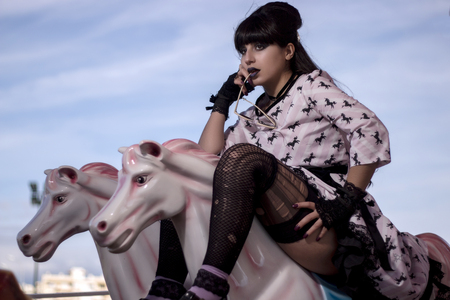 Cute pinup girl riding on a colorful carousel.の写真素材