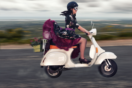 Vintage girl riding a classic motorcycle on the countryside road.の写真素材