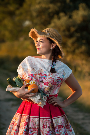 Vintage girl on the countryside with wicker hat gathering groceries.の写真素材