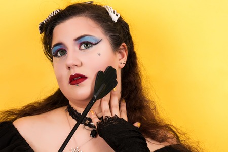 View of pinup vintage girl next to yellow backdrop teasing fetish.