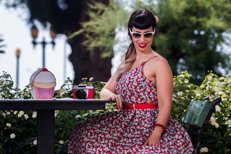 Pinup girl  with dress relaxing in the beautiful urban park.の写真素材