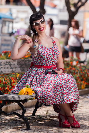 Pinup girl  with dress relaxing in the park, using a vintage camera.の写真素材