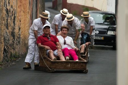 FUNCHAL, MADEIRA - 19th JUNE, 2017: Traditional toboggan men operating a wicker basket car with tourists.のeditorial素材