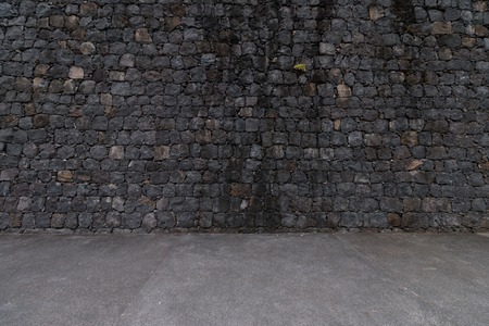 View of a dark stone wall background with ground.の写真素材