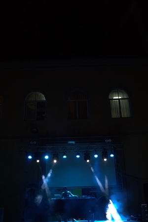 dj performing on a stage with blue lights and smoke.