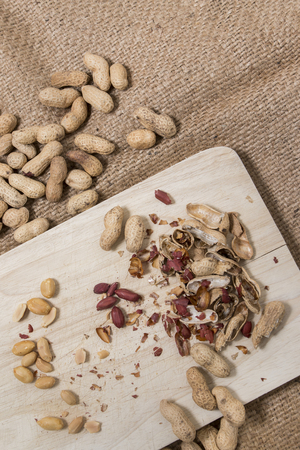 peanuts cracked and opened over a wooden board.