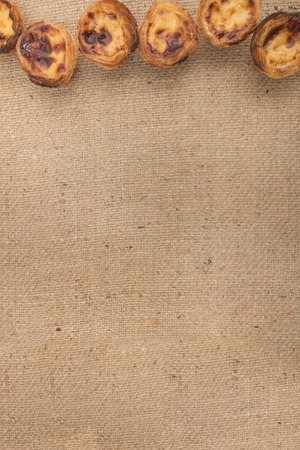 Famous Portuguese egg pastry tart called 'Pastel de Belem' on hessian fabric.