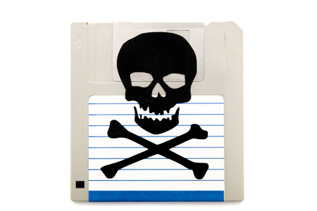 Close up view of a infected computer floppy disk isolated on a white background. Conceptual image with skull and bones.の写真素材
