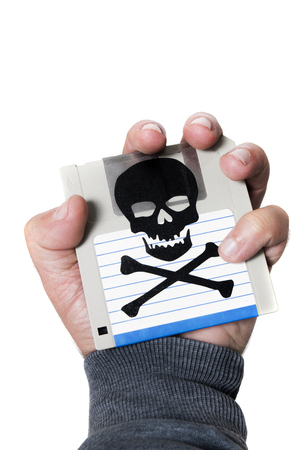 Hand holding a infected computer floppy disk isolated on a white background. Conceptual image with skull and bones.の写真素材
