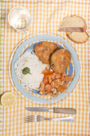 Fried hake fish with rice and tomato salad.の写真素材