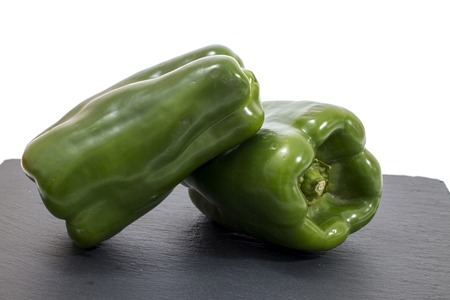 two green bell peppers on a black stone of schist.の写真素材
