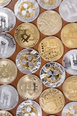 several aligned crypto currency coins on top of wooden table.の写真素材