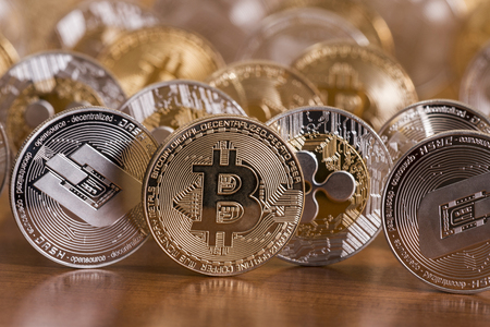 several aligned crypto currency coins on top of wooden table.の写真素材