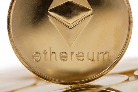 Shiny golden ethereum coin over a white background.