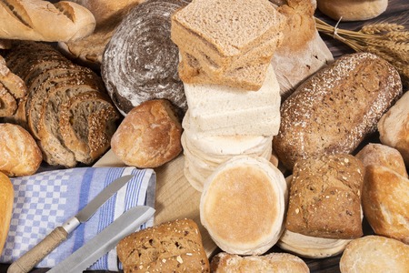 Fresh Assortment of several baked bread varieties on a wooden table.の写真素材