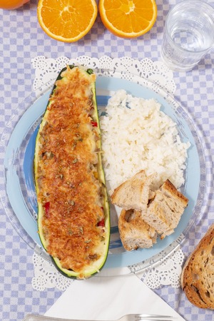 meat and vegetables zucchini halves with rice and bread.の写真素材