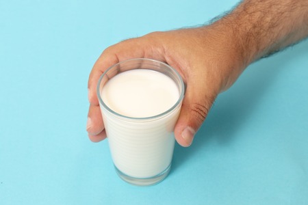 hand grabs glass of milk on a blue background.の写真素材