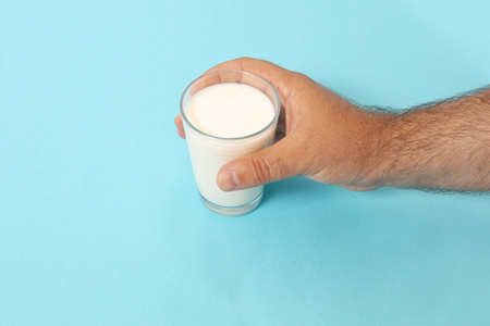 hand grabs glass of milk on a blue background.の写真素材