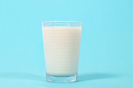 full glass of milk isolated on a blue background.の写真素材