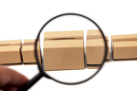 magnifying glass inspecting a cardboard box isolated over a white background.の写真素材