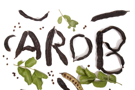 carob word made with carob fruit pods isolated over a white background.の写真素材