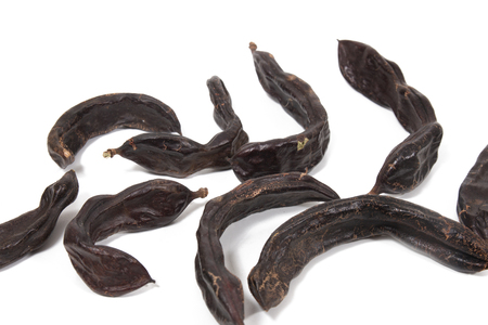 pile of carob fruits isolated over a white background.の写真素材