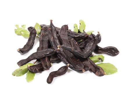 carob fruits with leafs isolated over a white background.の写真素材