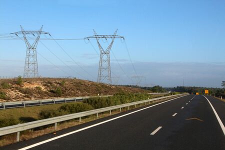 Close view of big electricity towers next to road.