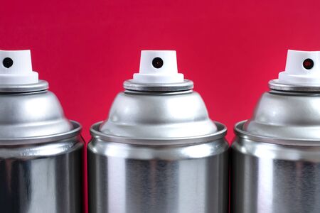 Close up view of silver spray cans on a red background.の写真素材