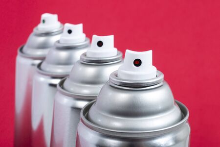 Close up view of silver spray cans on a red background.の写真素材