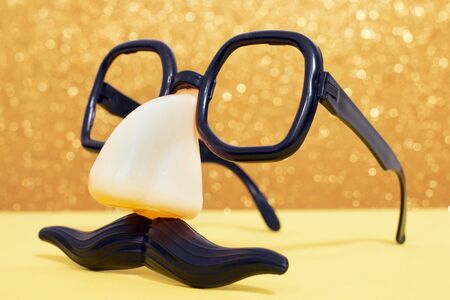 disguise masquerade glasses isolated on a golden background.の写真素材