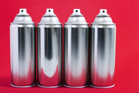 Close up view of silver spray cans on a red background.の写真素材