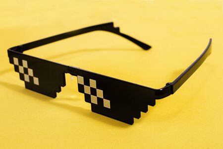 Close up view of meme pixel glasses isolated on a yellow background.の写真素材