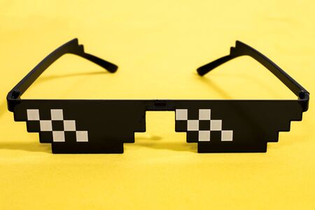 Close up view of meme pixel glasses isolated on a yellow background.の写真素材