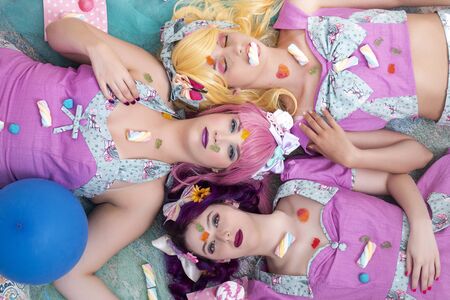 Three pinup girls with purple dresses on the ground posing with candy.の写真素材