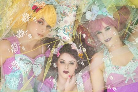 Three pinup girls with purple dresses on the ground posing.