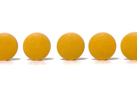 Group of orange pills over a white background.