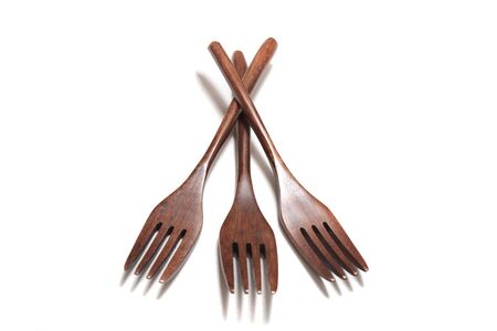 Close view of wooden forks over a white background.