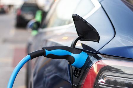 Close view of a Electric Car plugged in for charging on a charging station.
