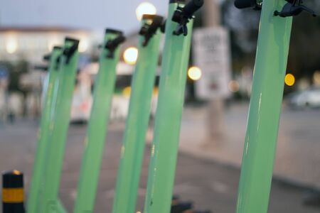 Green electric scooters for rent parked on the city.