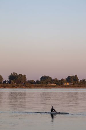One man practicing kayak on calm waters at the end of the day.の写真素材
