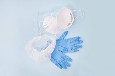 dust mask, blue gloves and head cover isolated on a light blue background.