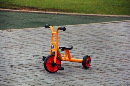 Close up view of a orange playground tricycle.
