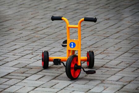 Close up view of a orange playground tricycle.
